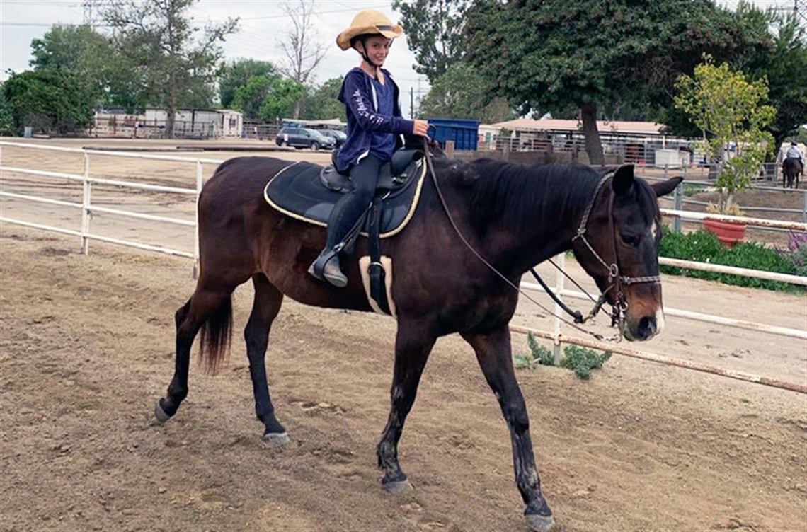 Smiling person riding horse