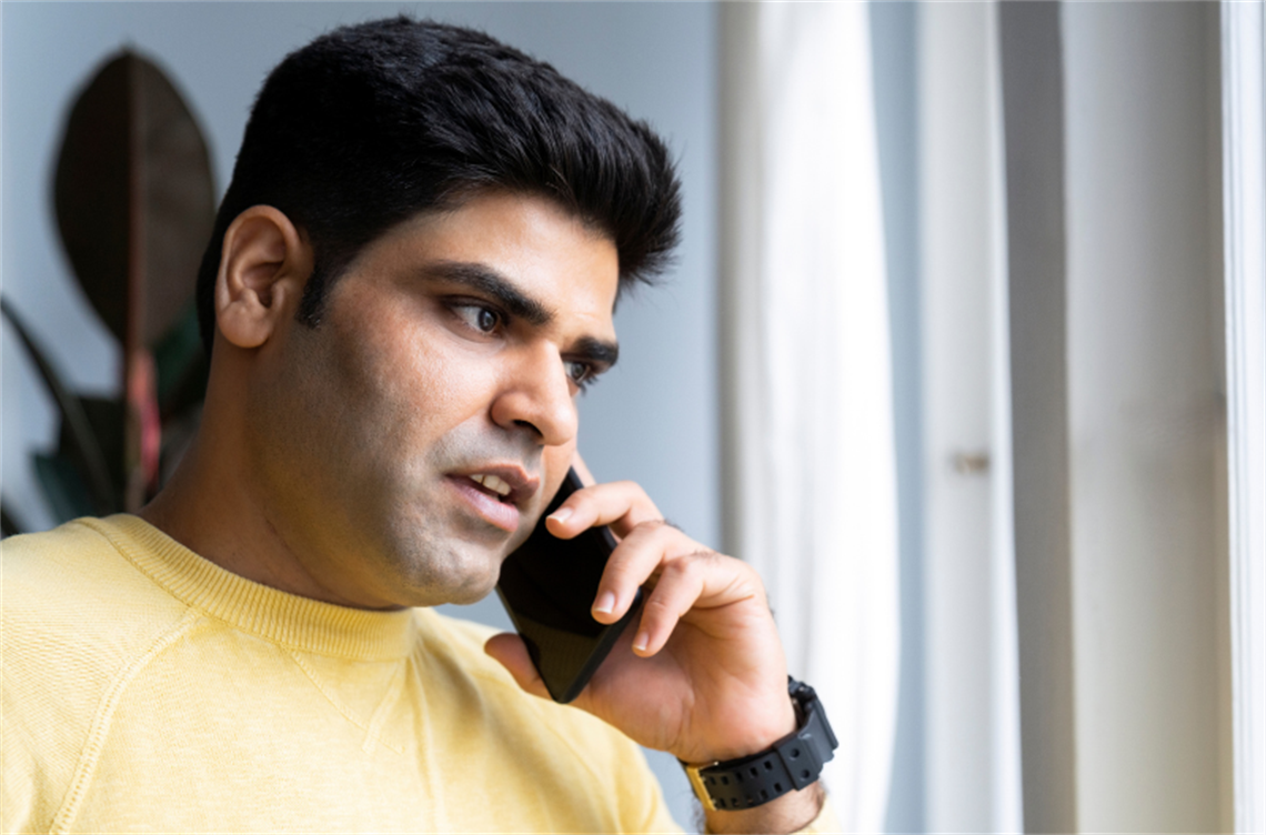 Man in yellow shirt talking on the phone